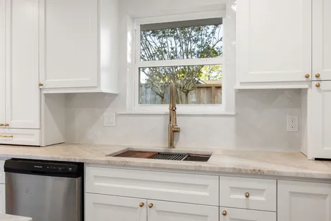 a large kitchen with stainless steel appliances kitchen island granite countertop a stove a sink and white cabinets