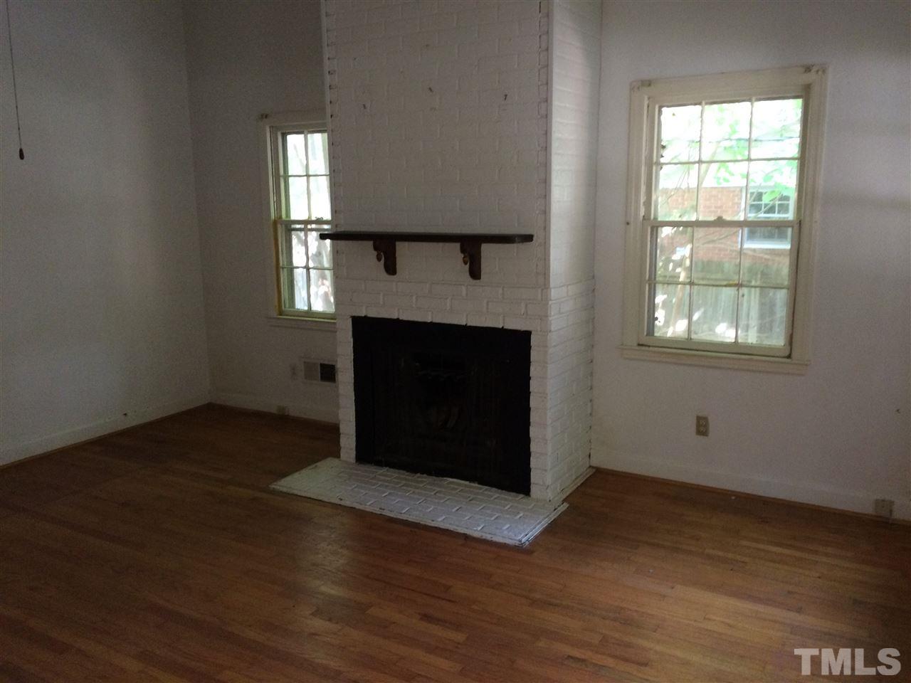 3129 Ward Road Raleigh, NC 27604 - Photo 3 of 9 an empty room with wooden floor windows and fireplace