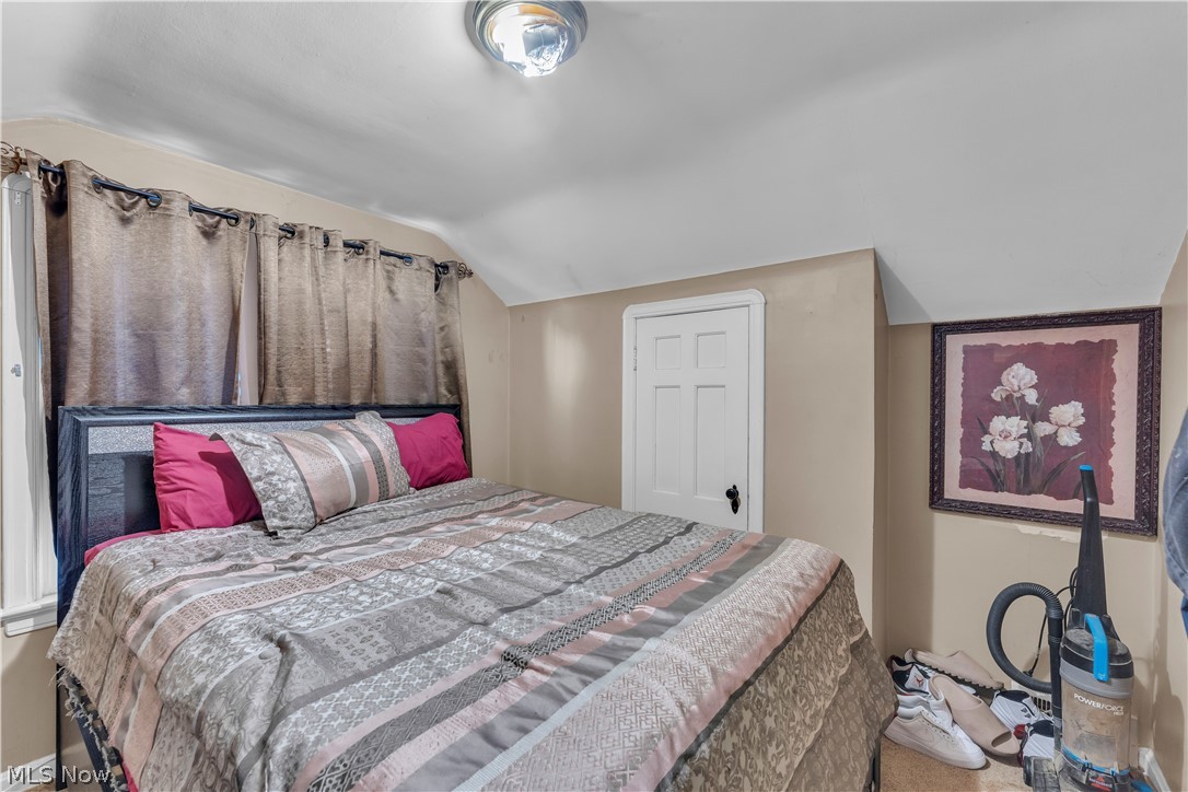 3962 Grosvenor Road South Euclid, OH 44118 - Photo 18 of 27 Bedroom featuring sloped ceilings, a classic paneled door with dark hardware, and neutral wall paint