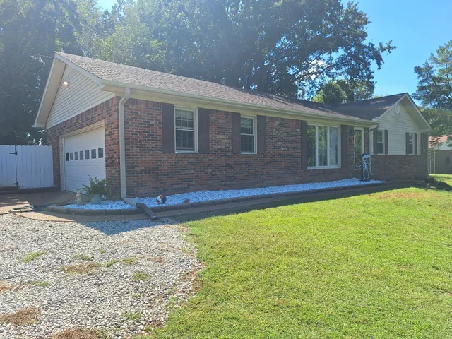 a front view of house with yard and trees in the background