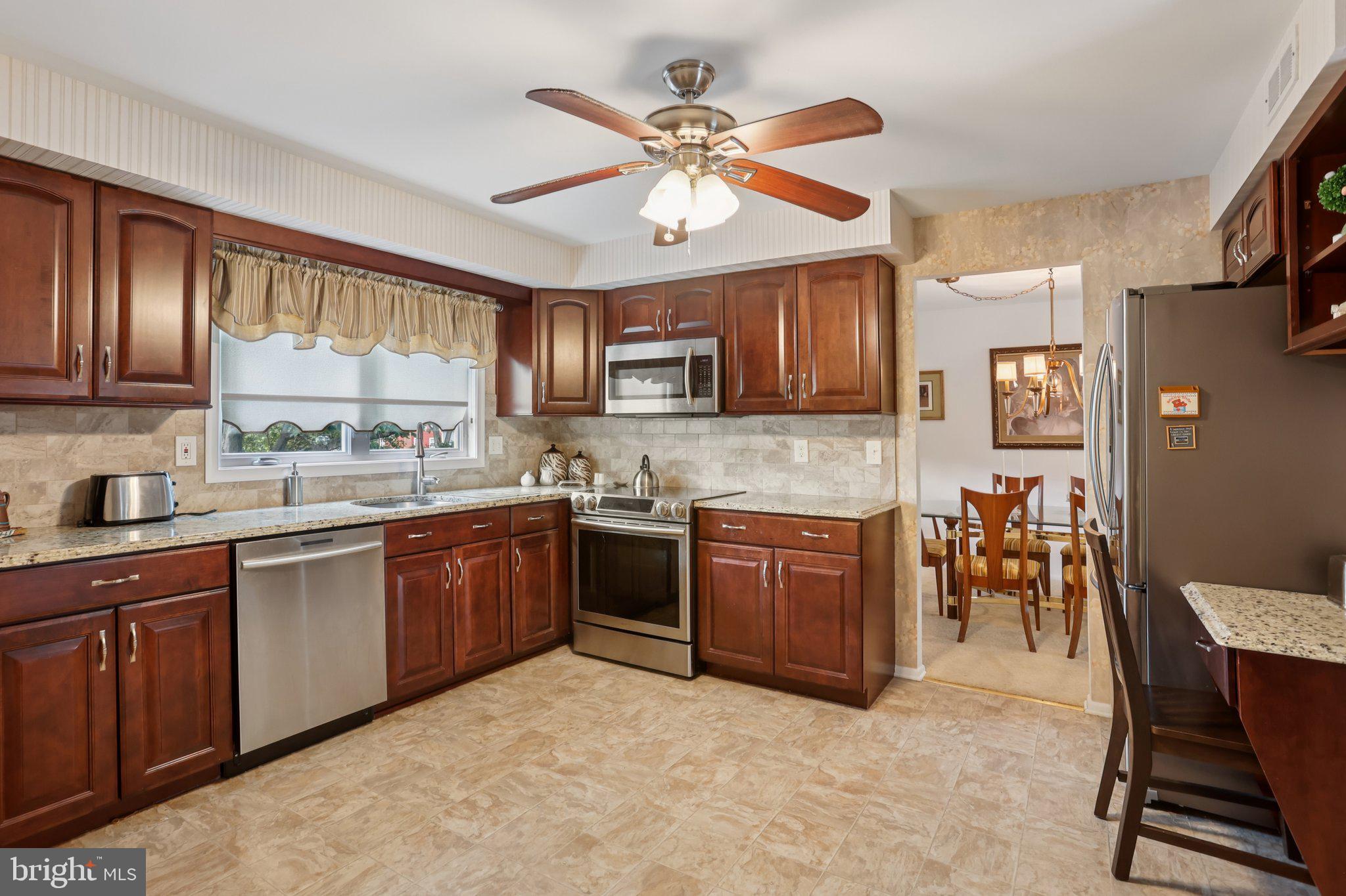 26 Regent Road Cherry Hill, NJ 08003 - Photo 16 of 36 a kitchen with stainless steel appliances granite countertop a stove top oven a sink a dining table and chairs with wooden floor