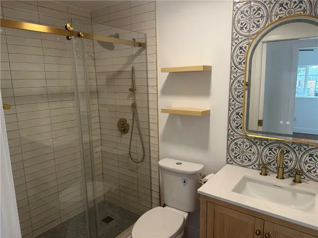 a bathroom with a toilet sink vanity and shower
