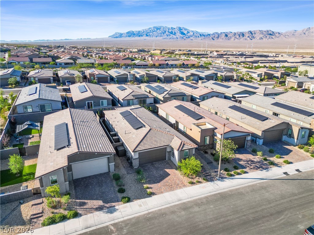 9398 Noble Fir Rdg Court Las Vegas, NV 89143 - Photo 31 of 36 An aerial perspective reveals a modern residential development with uniform homes, many equipped with rooftop solar panels, against a mountainous backdrop.