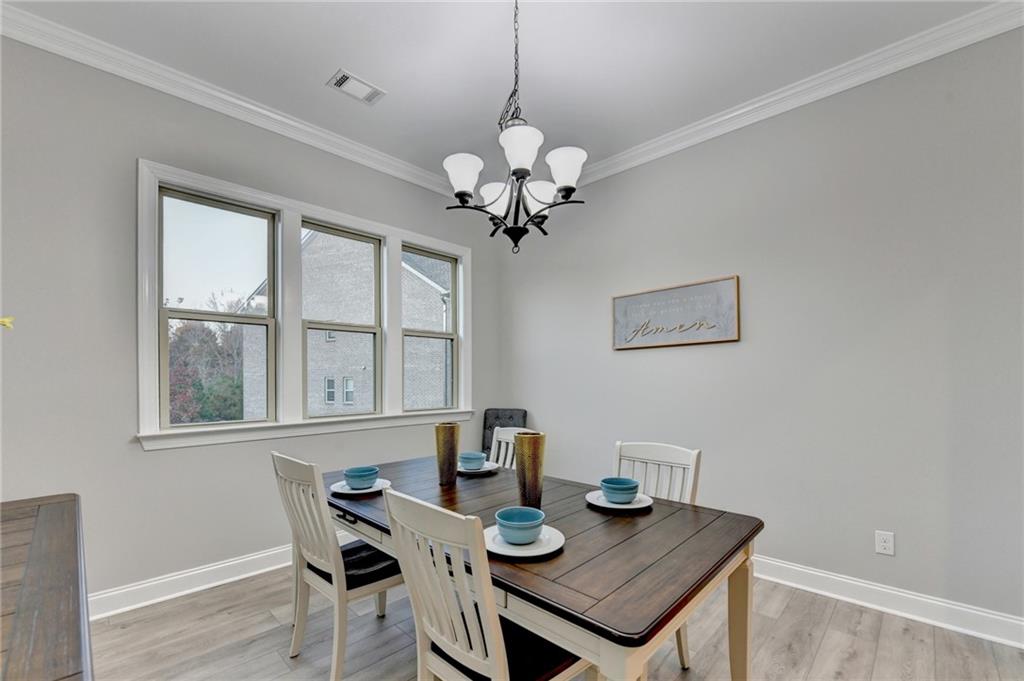 3907 Rustic Pine Lane Buford, GA 30518 - Photo 11 of 70 a view of a dining room with furniture a chandelier and wooden floor