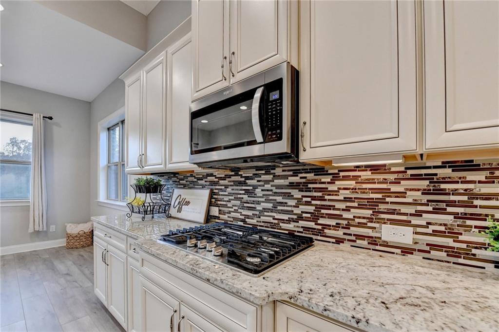 3907 Rustic Pine Lane Buford, GA 30518 - Photo 24 of 70 a kitchen with granite countertop a stove a microwave a sink and cabinets