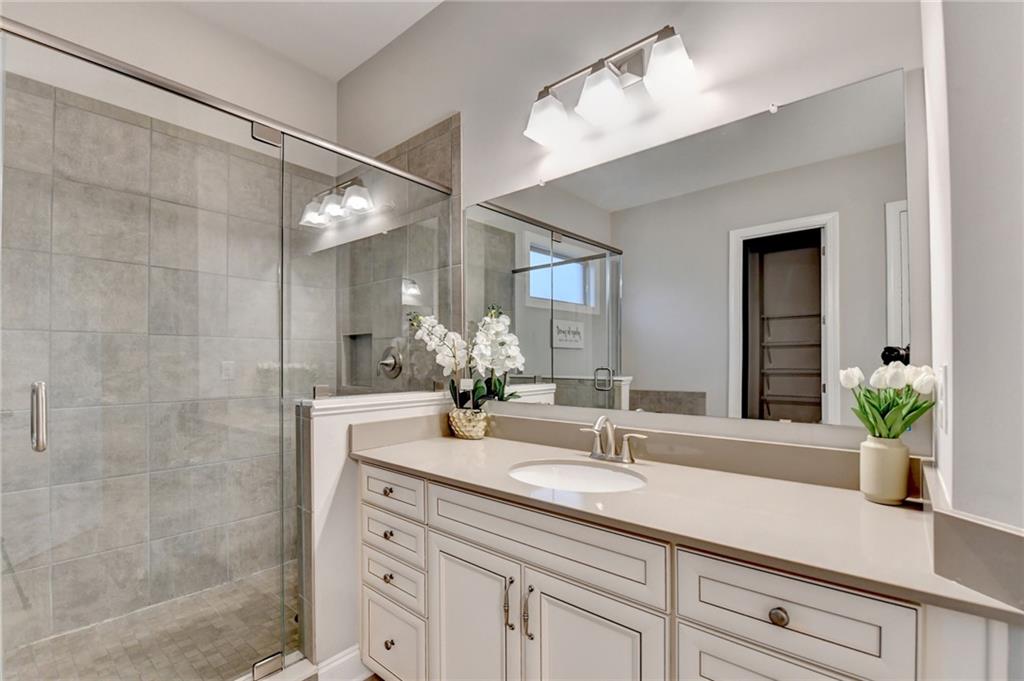 3907 Rustic Pine Lane Buford, GA 30518 - Photo 41 of 70 a bathroom with a granite countertop sink a mirror and a shower