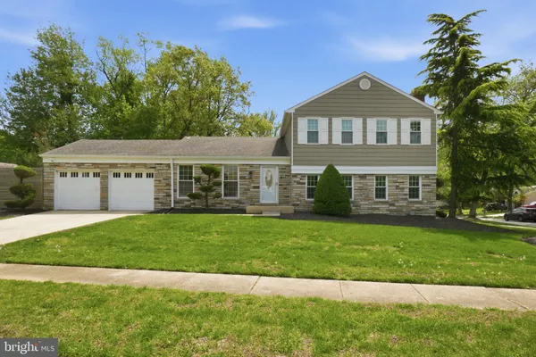a view of a house with a yard fire pit and a large tree