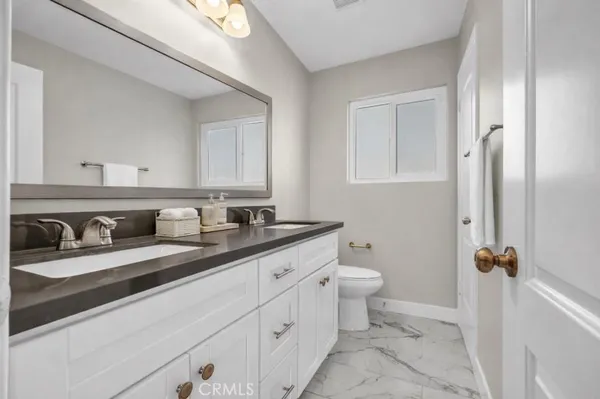 a bathroom with a granite countertop sink a toilet and a mirror