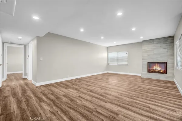 a view of an empty room with wooden floor and a fireplace