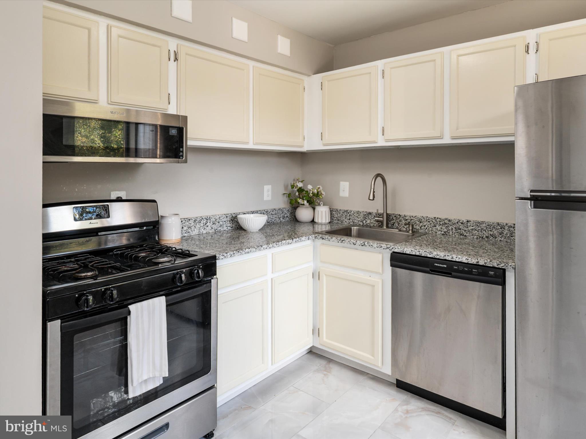 9639 White Acre Road, Unit B1 Columbia, MD 21045 - Photo 13 of 23 a kitchen with stainless steel appliances granite countertop white cabinets sink and stove