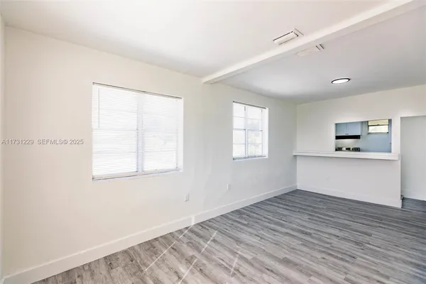 a view of empty room with wooden floor and window