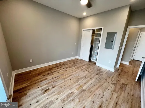a view of an empty room with wooden floor and a bathroom