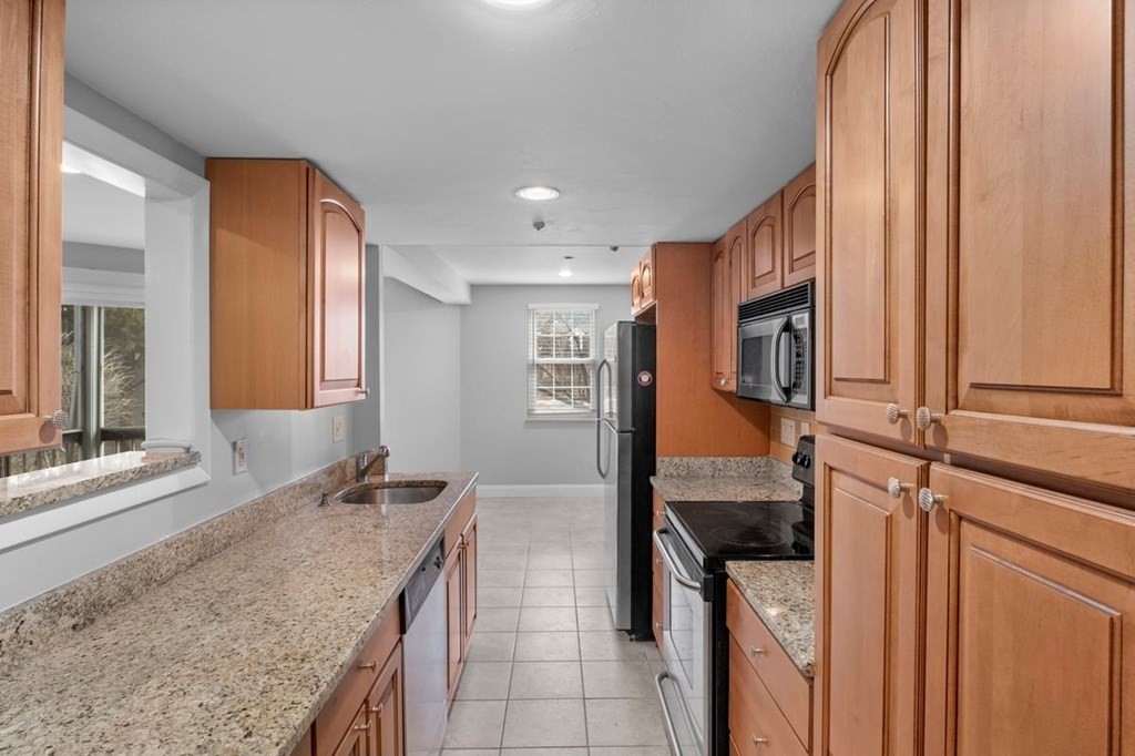 33 Christopher Drive, Unit A Stoughton, MA 02072 - Photo 5 of 23 a kitchen with stainless steel appliances granite countertop a sink and a refrigerator