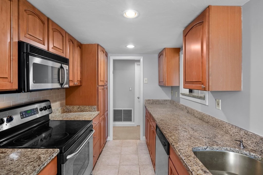 33 Christopher Drive, Unit A Stoughton, MA 02072 - Photo 7 of 23 a kitchen with stainless steel appliances granite countertop a stove a sink and a microwave