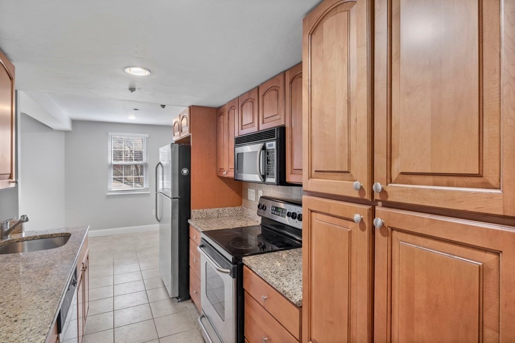 33 Christopher Drive, Unit A Stoughton, MA 02072 - Photo 8 of 23 a kitchen with stainless steel appliances granite countertop a sink stove and refrigerator