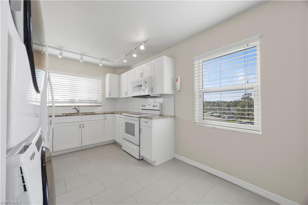 4372 27th Court Southwest, Unit 301 Naples, FL 34116 - Photo 11 of 37 a kitchen with white cabinets and white appliances