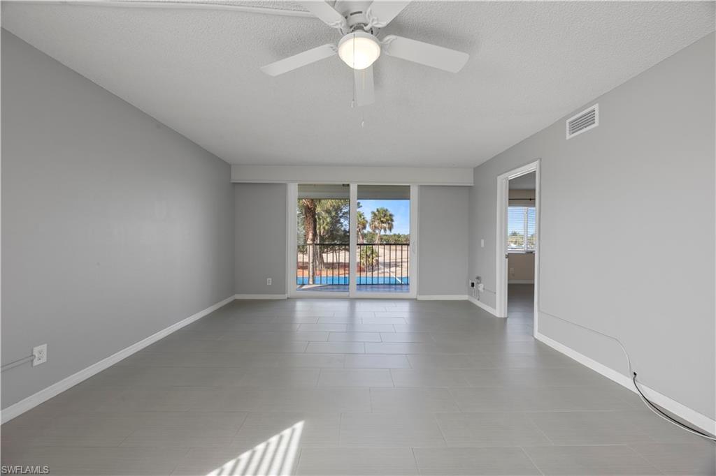 4372 27th Court Southwest, Unit 301 Naples, FL 34116 - Photo 16 of 37 an empty room with chandelier fan and windows