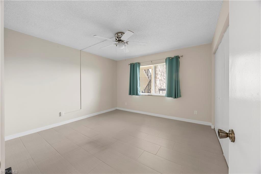 4372 27th Court Southwest, Unit 301 Naples, FL 34116 - Photo 26 of 37 an empty room with windows and ceiling fan