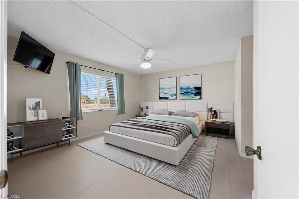 4372 27th Court Southwest, Unit 301 Naples, FL 34116 - Photo 5 of 37 a spacious bedroom with a bed and a flat tv screen on the dresser