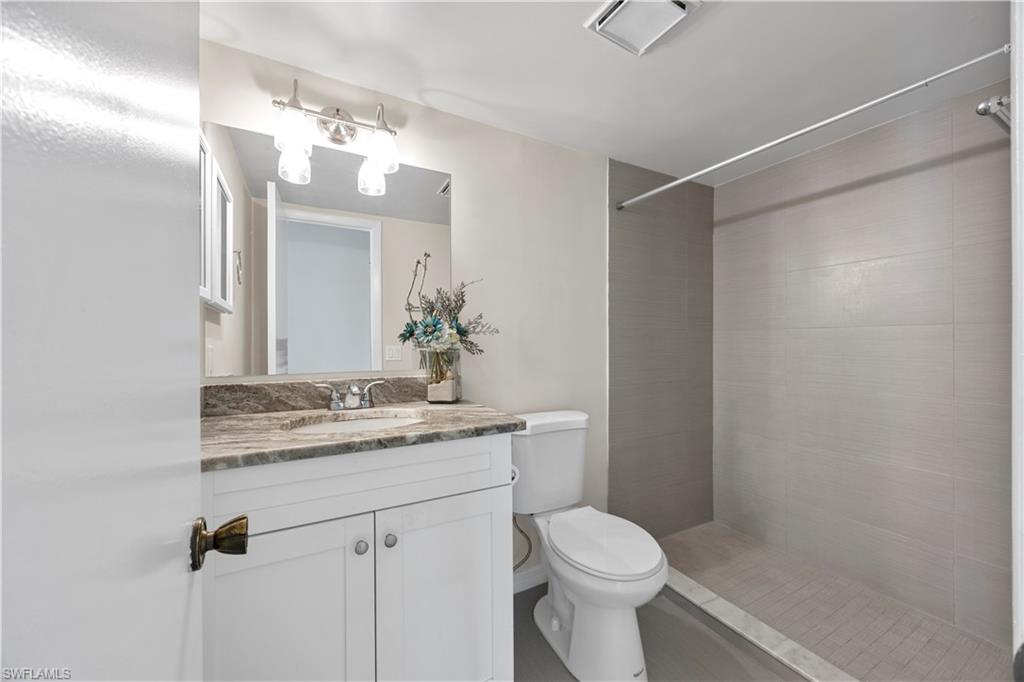 4372 27th Court Southwest, Unit 301 Naples, FL 34116 - Photo 6 of 37 a bathroom with a granite countertop sink a toilet and a mirror