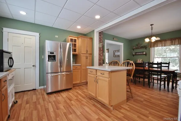 a kitchen with stainless steel appliances granite countertop a refrigerator a microwave oven a sink with island and chairs