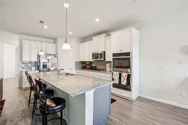 a kitchen with stainless steel appliances granite countertop a table chairs refrigerator and microwave