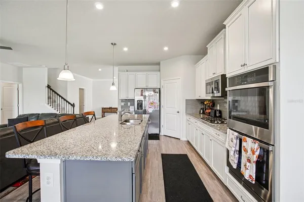 a large kitchen with granite countertop a large counter top appliances and cabinets