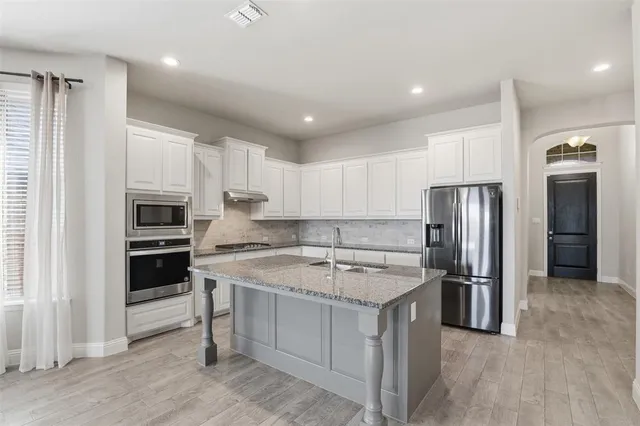a kitchen with granite countertop a sink stainless steel appliances and white cabinets