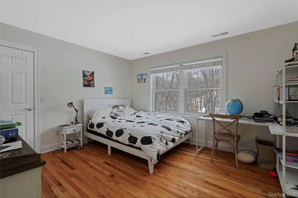 a bed sitting in a bedroom next to a window with chair and wooden floor