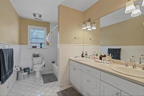 a bathroom with a double vanity sink a toilet and a mirror