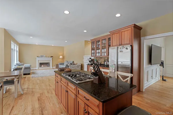 a kitchen with stainless steel appliances granite countertop a stove a refrigerator a sink and white cabinets with wooden floor