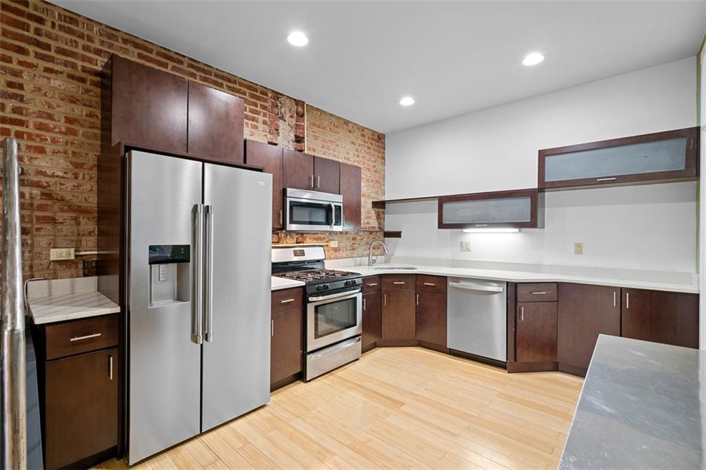 1402 James Street Pittsburgh, PA 15212 - Photo 10 of 30 a kitchen with stainless steel appliances granite countertop a refrigerator a sink dishwasher a stove and white countertops with wooden floor