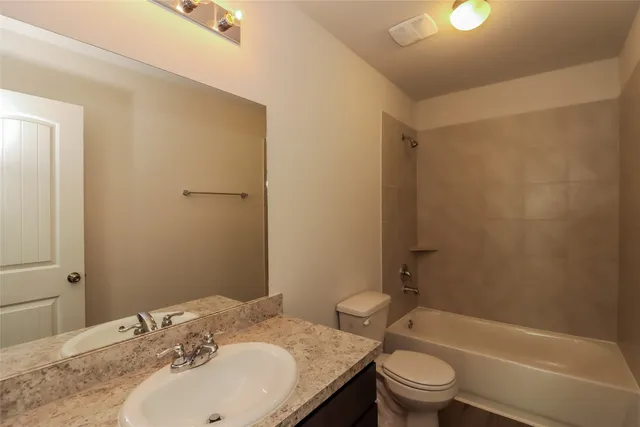 a bathroom with a granite countertop sink toilet and shower