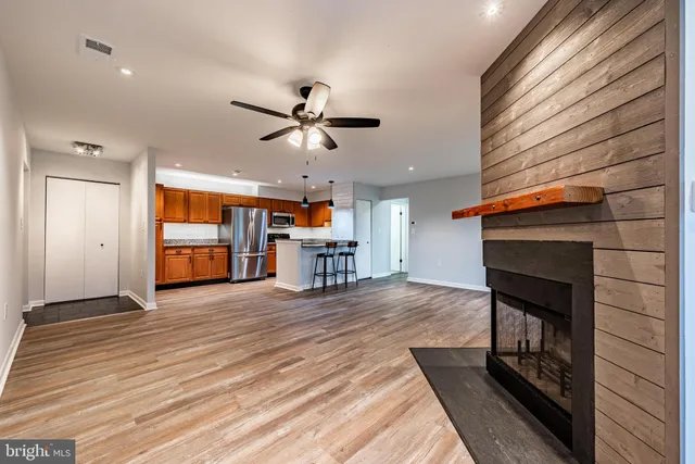 an empty room with wooden floor a ceiling fan and windows