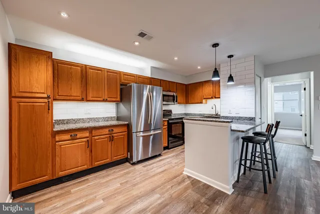 a kitchen with granite countertop stainless steel appliances a refrigerator a stove top oven and sink