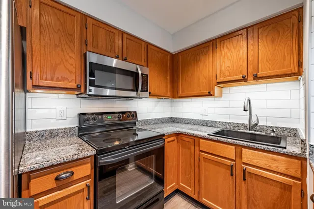 a kitchen with granite countertop cabinets stainless steel appliances a sink and wooden floor