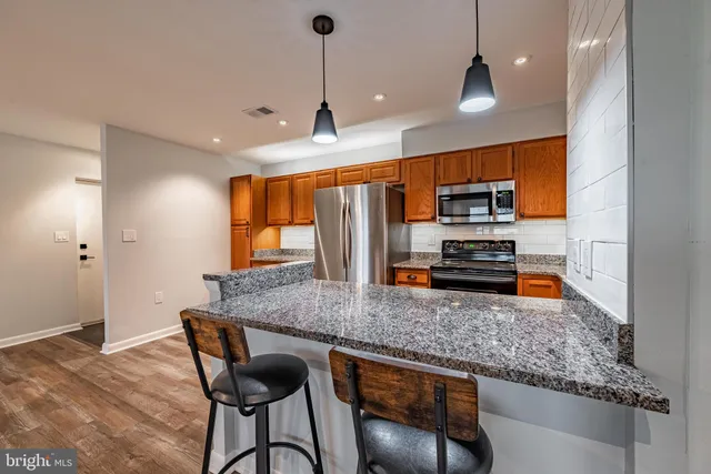 a kitchen with stainless steel appliances granite countertop a stove a sink a microwave a dining table and chairs with wooden floor