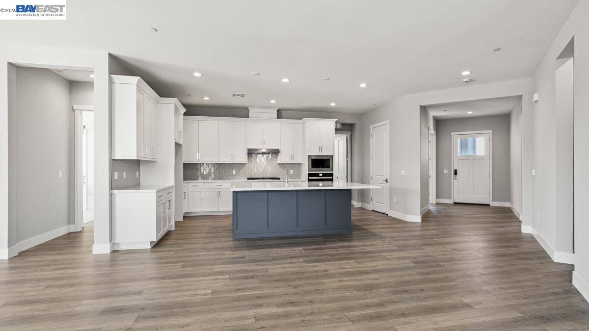 756 Conrad Street Manteca, CA 95336 - Photo 4 of 41 a large kitchen with a center island wooden floor stainless steel appliances and a window