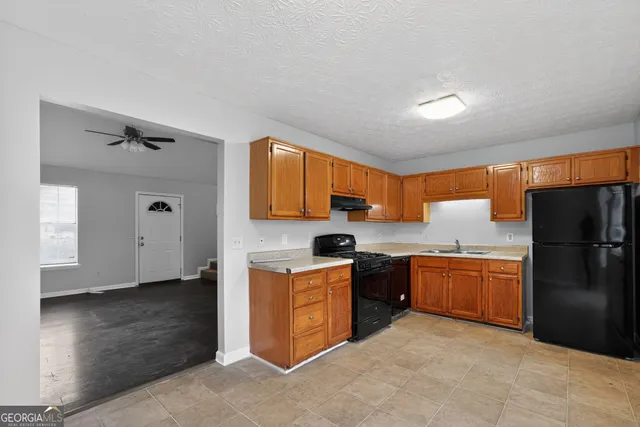 a kitchen with granite countertop stainless steel appliances a refrigerator cabinets and wooden floor