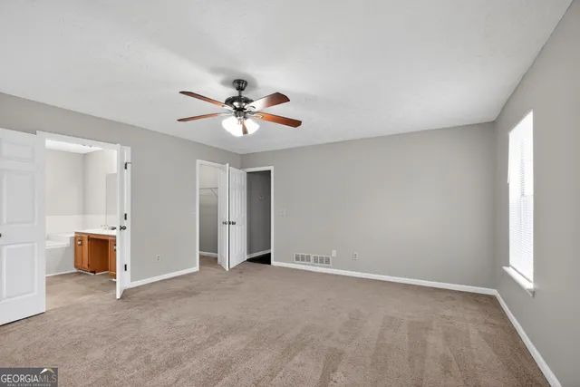 a view of an empty room with a ceiling fan and window