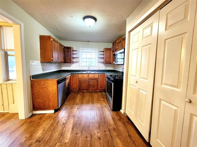 a large kitchen with stainless steel appliances granite countertop a stove a sink and a refrigerator