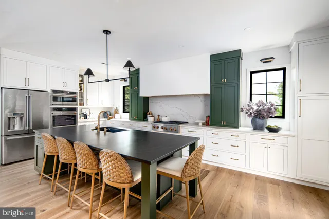 a kitchen with stainless steel appliances kitchen island granite countertop a table chairs stove and refrigerator