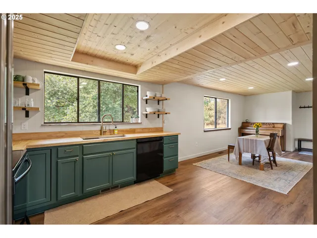 a open kitchen with stainless steel appliances granite countertop a sink and dishwasher a large window with wooden floor