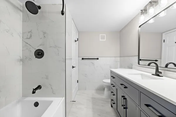 a bathroom with a tub sink vanity and shower