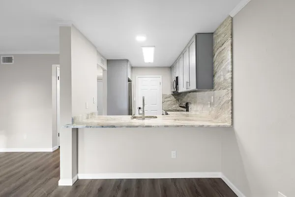 a view of a kitchen with kitchen island a sink wooden floor and black appliances