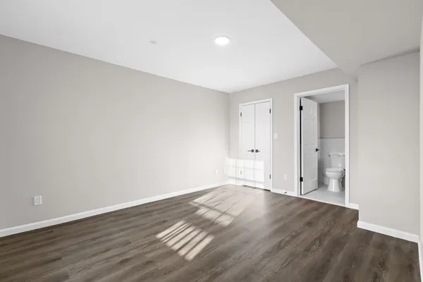 a view of an empty room with wooden floor and closet