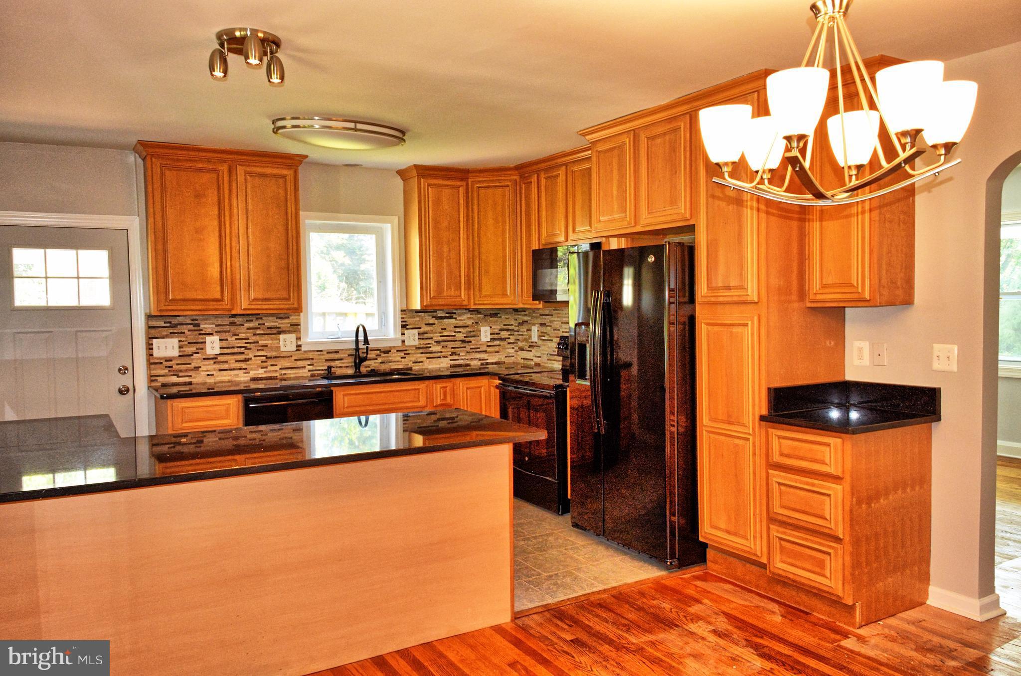 12408 Regwood Road Hydes, MD 21082 - Photo 5 of 17 a kitchen with stainless steel appliances wooden floor and a refrigerator