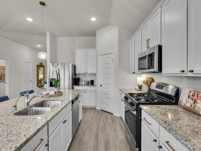 a kitchen with stainless steel appliances granite countertop a refrigerator a stove top oven a sink dishwasher and wooden cabinets