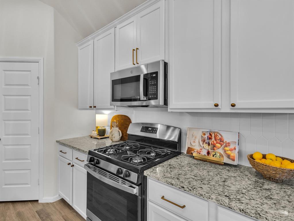 13141 Yellowstone Way Providence Village, TX 76227 - Photo 15 of 40 a kitchen with stainless steel appliances granite countertop a stove a microwave and cabinets