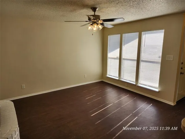 an empty room with wooden floor fan and windows